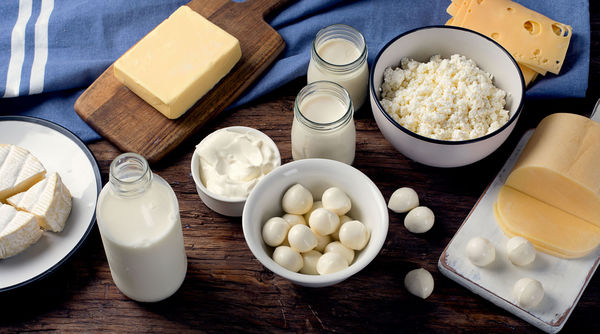 Verschiedene Lactoseprodukte wie Milch, Eier und Käse auf einem Holztisch