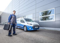 Blueserv Mitarbeiter mit Werkzeugkoffer vor gebrandeten Blueserv Auto